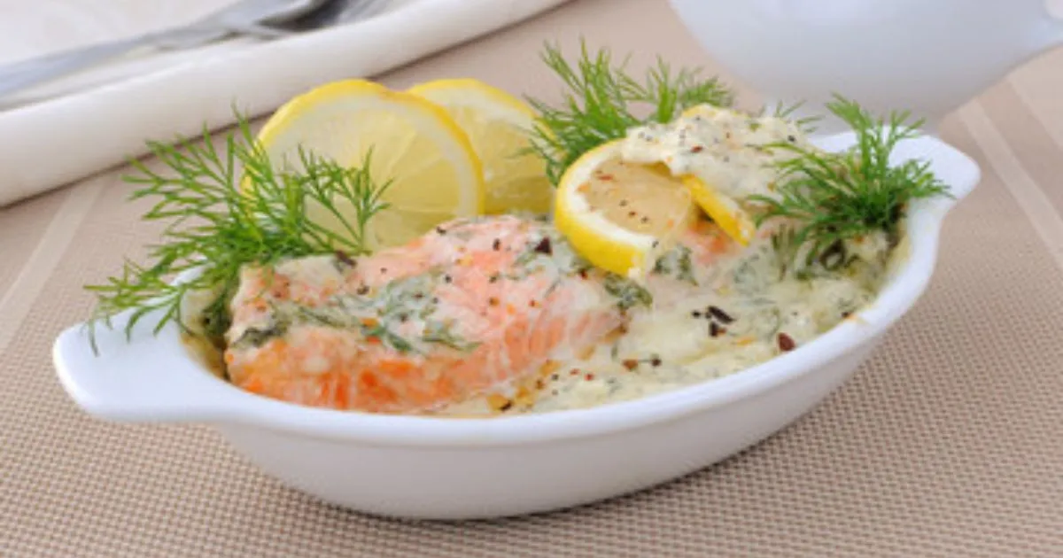 Pan-seared Lemon Butter Salmon fillet with fresh herbs and lemon wedges.
