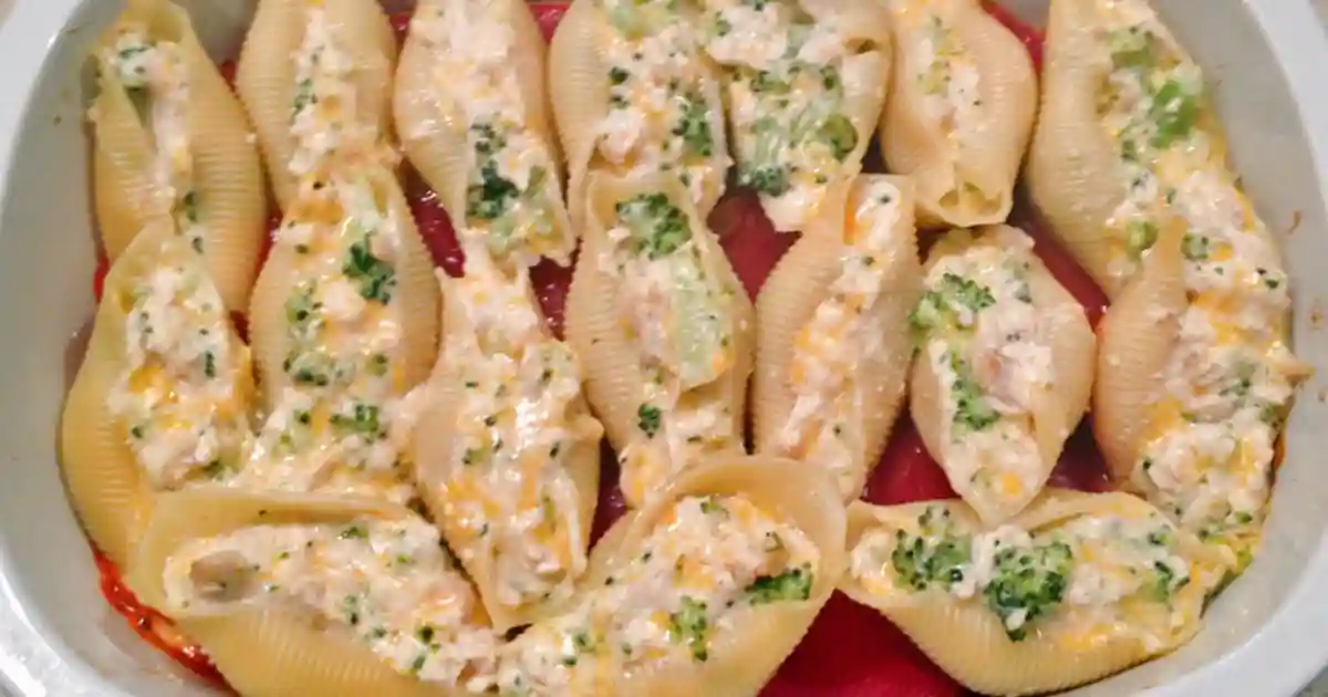 A plate of creamy chicken alfredo stuffed shells topped with melted cheese and fresh parsley, served on a rustic wooden table with a side of garlic bread.